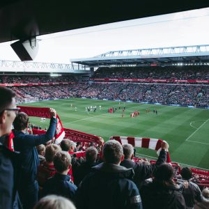 Fans cheer as players take the field at a vibrant football stadium, creating an electric atmosphere.